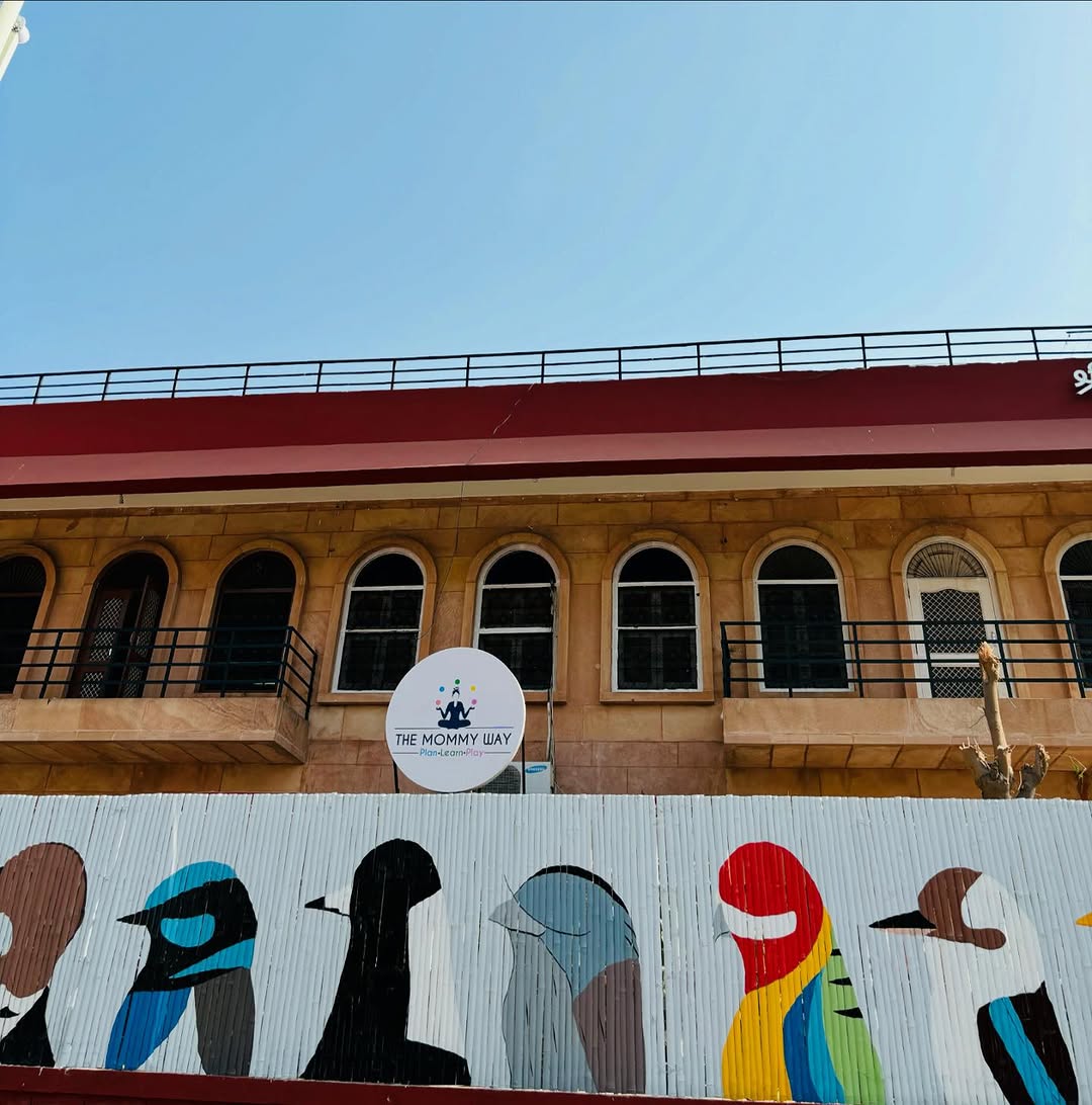 The Mommy Way sign on the sandstone building in Ratanada, above a painted mural of birds